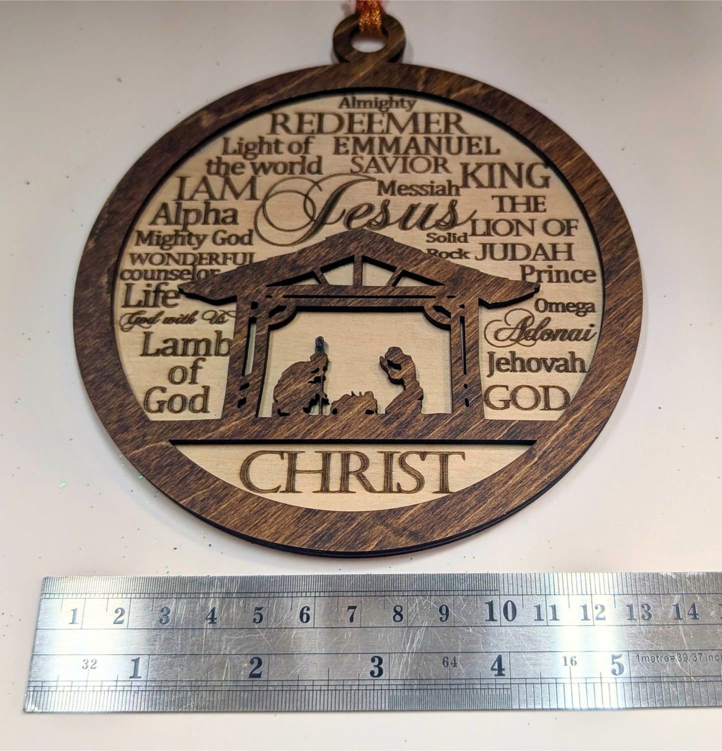 Engraved wooden nativity ornament with Christian titles and a ruler for scale, handcrafted by Great Scott Woodworks