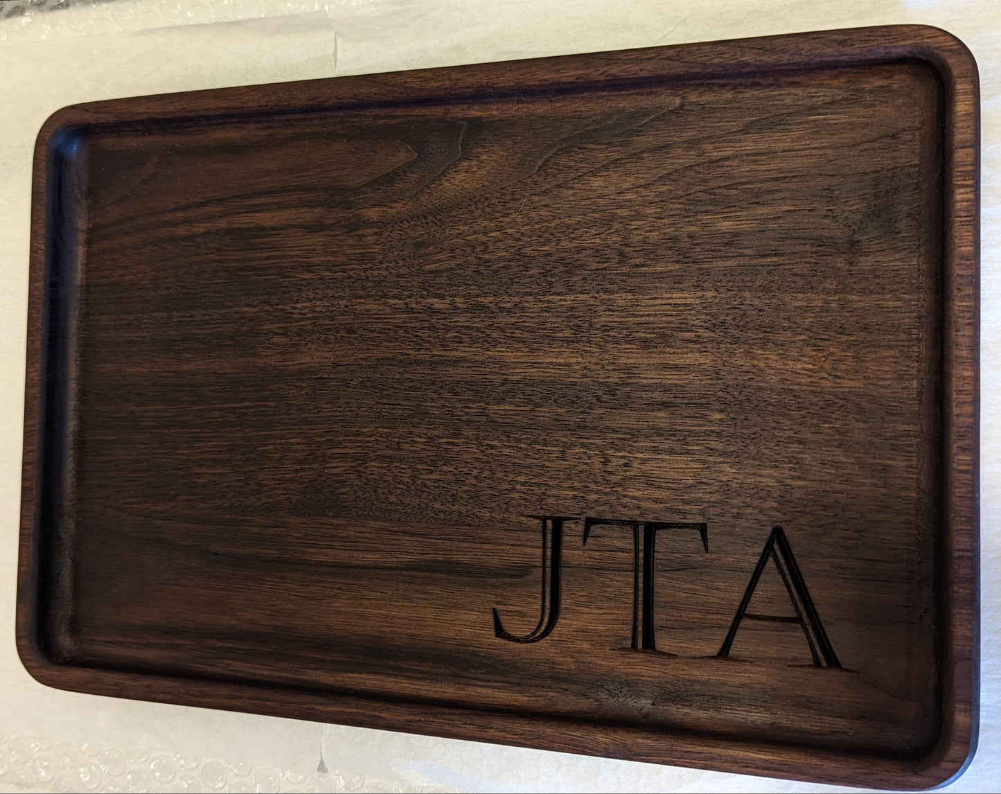 Large personalized walnut catch-all tray with initials JTA engraved in lower right corner, featuring dark natural wood tone variation