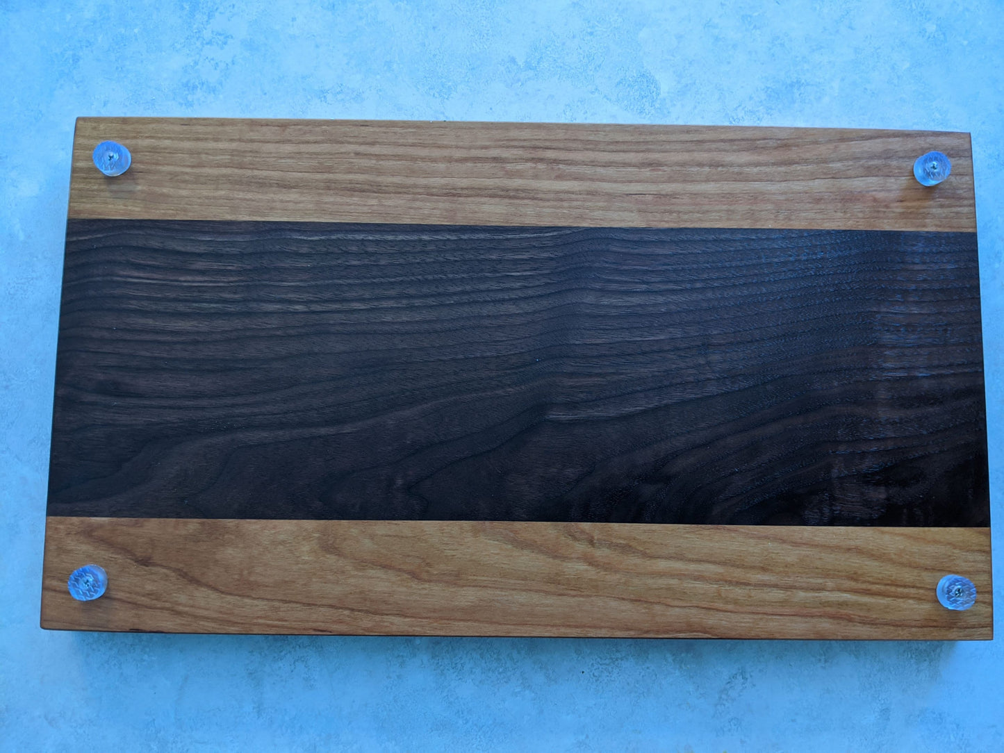 Walnut and cherry face‑grain cutting board with dark walnut center, cherry edges, and rubber feet, handcrafted by Great Scott Woodworks