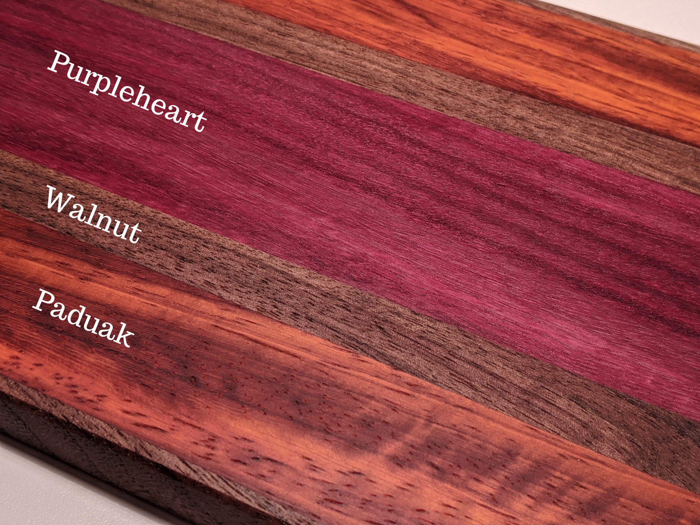 Handmade face-grain bar board with walnut, purpleheart, and padauk wood types labeled by Great Scott Woodworks