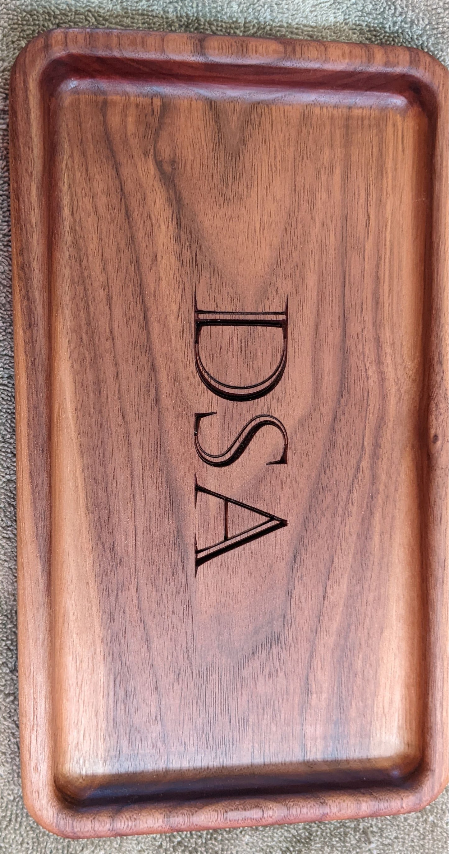 Personalized walnut catch-all tray with initials DSA engraved in the center, and showing a lighter natural wood tone variation