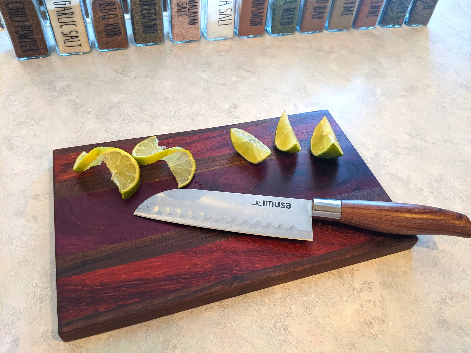 Handmade walnut purpleheart padauk bar board in use on counter with cut limes and knife by Great Scott Woodworks